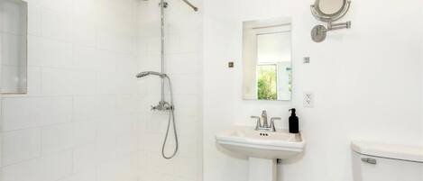 Ein Badezimmer mit Dusche, Waschbecken, Toilette und einem wandmontierten Spiegel.
