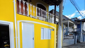 A yellow building with a balcony, a garage, and a visible address number.