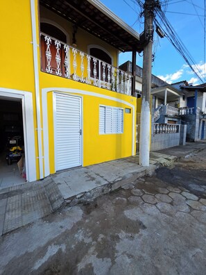 A yellow building with a balcony, a garage, and a visible address number.