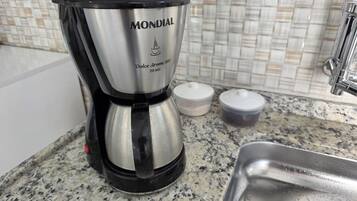 A stainless steel Mondial coffee maker on a granite countertop with a tiled backsplash and a stainless steel sink.