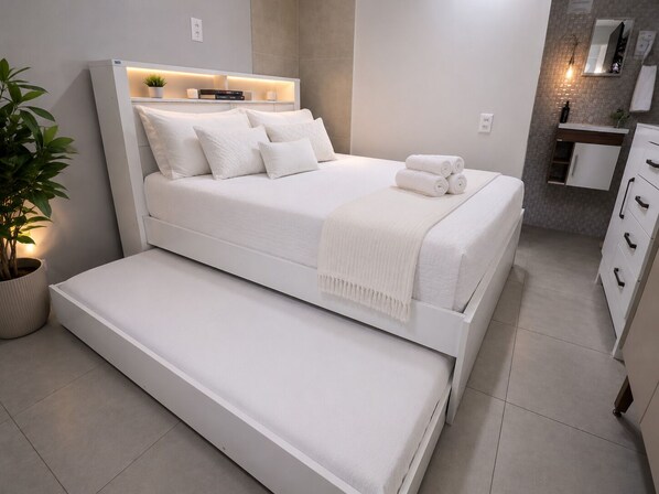 A modern bedroom with a bed, bedside table, and a small seating area.