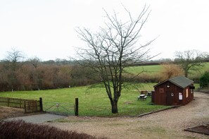 A rural property with a fenced area, a small wooden building, and a tree.