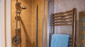 A glass-enclosed shower with a handheld showerhead and a handheld shower attachment. - The Masons Arms (Odcombe)