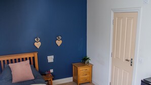 A bedroom with a bed, a nightstand, a dresser, a ceiling fan, and a door. - The Masons Arms (Odcombe)