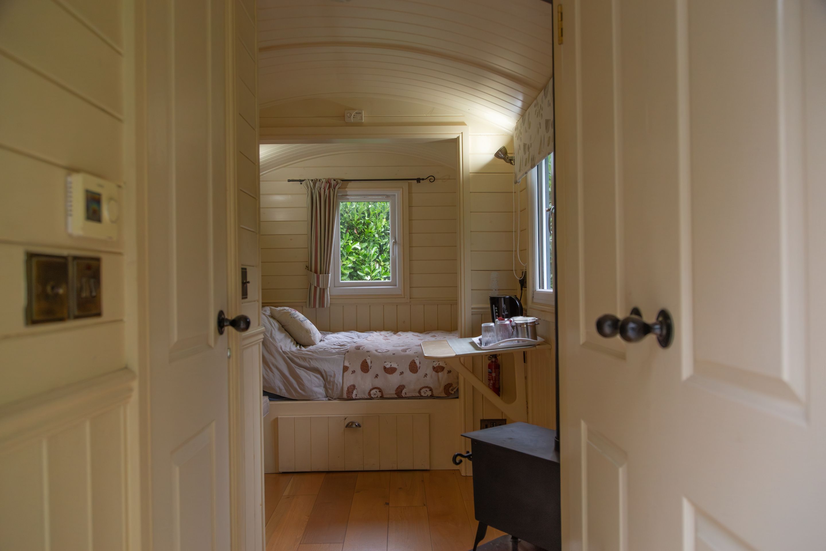 A bedroom with a bed, a window with curtains, a bedside table, and a radiator.