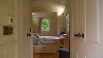 A bedroom with a bed, a window with curtains, a bedside table, and a radiator.