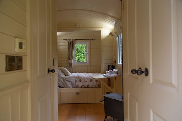 A bedroom with a bed, a window with curtains, a bedside table, and a radiator.