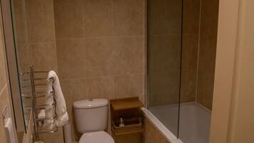 Un baño pequeño con inodoro, lavamanos y ducha.