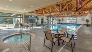 A pool area with a hot tub, lounge chairs, and a table.