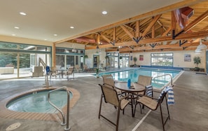 Un área de piscina con jacuzzi, sillones reclinables y una mesa.