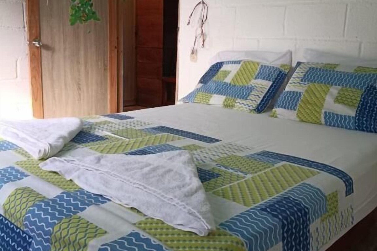 Una habitación con una cama, una puerta de madera y una pared de ladrillo blanco.