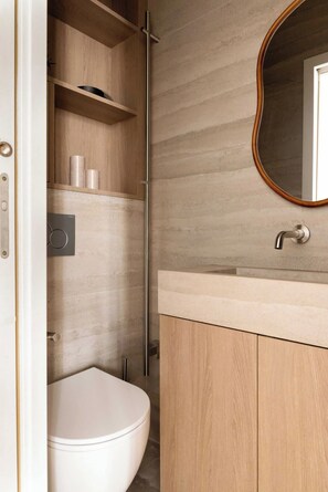 Ein modernes Badezimmer mit Toilette, einem Holzkosmetikschrank, einem Spiegel und einer Dusche.