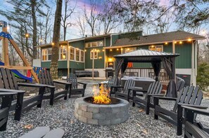 Eine Terrasse mit Sitzgelegenheiten im Freien, einer Feuerstelle und einer Spielanlage.