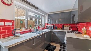 A modern kitchen with a large window, stainless steel appliances, and red-tiled backsplash.