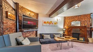 A cozy living room with a fireplace, a flat-screen TV, and a sofa.