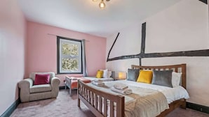 A bedroom with a wooden bed, a chair, a bedside table, and a window.