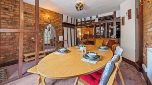 A dining area with a round wooden table, chairs, and a brick wall.
