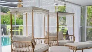 Una habitación con cuatro camas con dosel, una piscina y ventanas amplias.