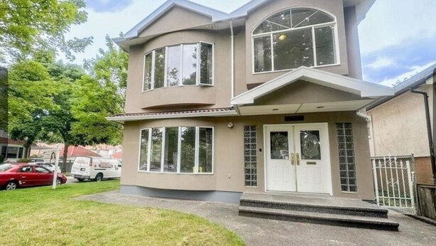 Une maison à deux étages avec un porche à l’avant, de grandes fenêtres et un garage.