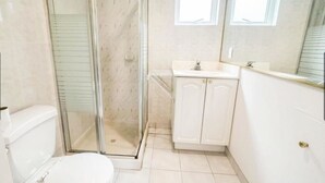 Une salle de bain comprenant des toilettes, un espace douche, un lavabo et un miroir.