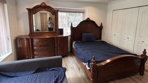 Une chambre à coucher avec un lit en bois, une commode, un miroir et une armoire.