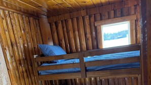 A bunk bed with a window, wooden walls, and a view of the outdoors. - Adorable 2-bedroom cabin with AC in charming Cheboygan (Cheboygan)
