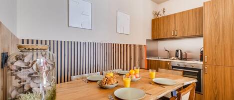 Eine moderne Küche mit Holzschränken, einem für das Frühstück gedeckten Esstisch und einem dekorativen Glas mit getrockneten Blumen.