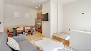 Una sala de estar moderna con un sofá gris, una mesa de centro blanca y un comedor con sillas de madera y una mesa.