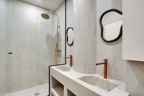 A modern bathroom with a glass shower enclosure, two sinks with copper faucets, and a large mirror. - Modern Apartment - 2bd/8p - Place D'italie (Paris)