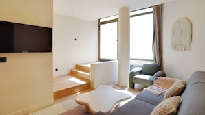Una sala de estar moderna con un sofá, una mesa de centro y un televisor montado en la pared.