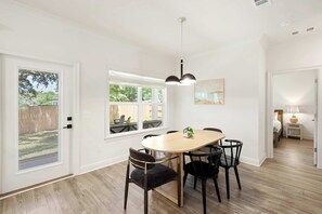 Ein Essbereich mit Holztisch und -stühlen, einer Pendelleuchte und Blick durch große Fenster.