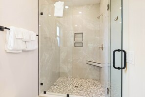 A glass-enclosed shower with a tiled floor, a towel rack, and a glass door with a handle. - Spacious 3 Bedroom Home Near Beaches and Shopping! (Pensacola)