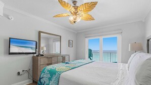 Ein Schlafzimmer mit Bett, Deckenventilator, Fernseher, Schminktisch und einem Balkon mit Aussicht.