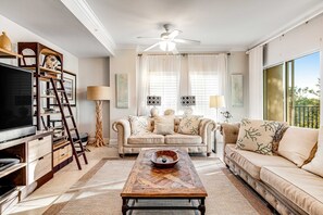 Ein Wohnzimmer mit Fernseher, Holz-Couchtisch, Sofa und Deckenventilator.
