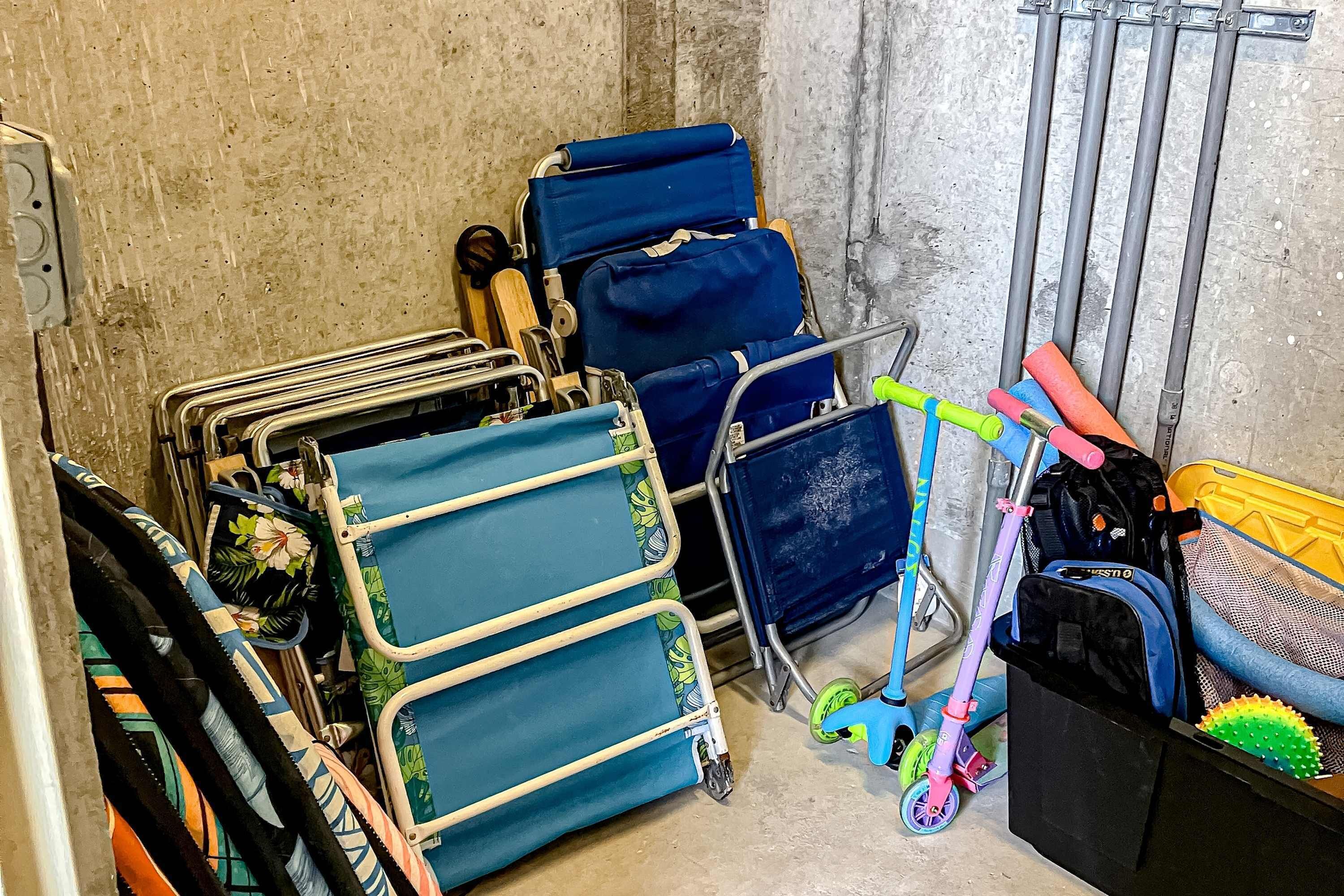 A storage area with various items including a blue folding chair, a scooter, and a black bag.