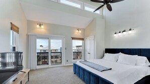 Ein Schlafzimmer mit Bett, einer Bank, einem Deckenventilator und einem Balkon mit Aussicht.