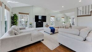 Ein geräumiges Wohnzimmer mit Kamin, Sofas und Fernseher.