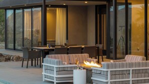 Un patio moderno al aire libre con piscina, zona de estar y una chimenea.