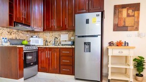 Una cocina con gabinetes de madera, un refrigerador de acero inoxidable, un microondas y una estufa.