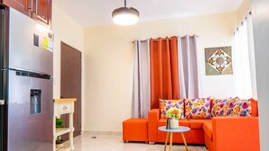 Un espacio habitable compacto con kitchenette, un conjunto de sofás y un adorno en la pared.