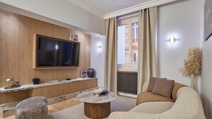 A modern living room with a flat-screen TV, a round coffee table, a sofa, and a decorative vase. - Luxurious Airconditioned Apartment Arc de Triomphe (Paris)