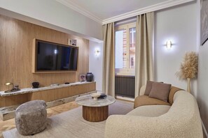 Ein modernes Wohnzimmer mit Flachbildfernseher, rundem Couchtisch, einer Couch und einer dekorativen Vase.