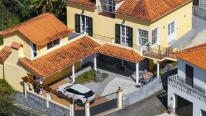 Ein mehrgeschossiges Haus mit einem Ziegeldach, einem Auto auf der Auffahrt und einem verschlossenen Eingang.
