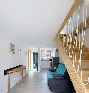 Ein modernes Interieur mit einer Holztreppe, einem Sofa, einem Esstisch und einer Küchenzeile.