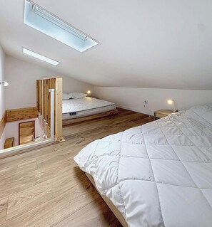 Ein Schlafzimmer mit Schlafgalerie, einem Bett, einem Schreibtisch und einem Stuhl.