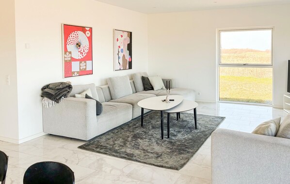 Ein modernes Wohnzimmer mit einem grauen Sofa, einem runden Couchtisch und zwei abstrakten Bildern an der Wand.