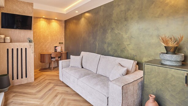 Uma sala de estar moderna com sofá, área de jantar e televisão na parede.