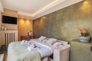Ein modernes Hotelzimmer mit Bett, Fernseher, kleinem Tisch und Schrank.