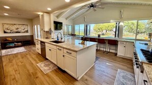 Una cocina moderna con una isla grande, suelo de madera y un ventilador de techo.