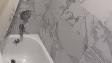 Une salle de bain avec une baignoire, une douche et des carreaux à motifs de marbre.
